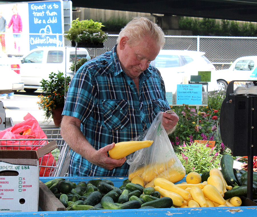 Photo of man selecting squash at market